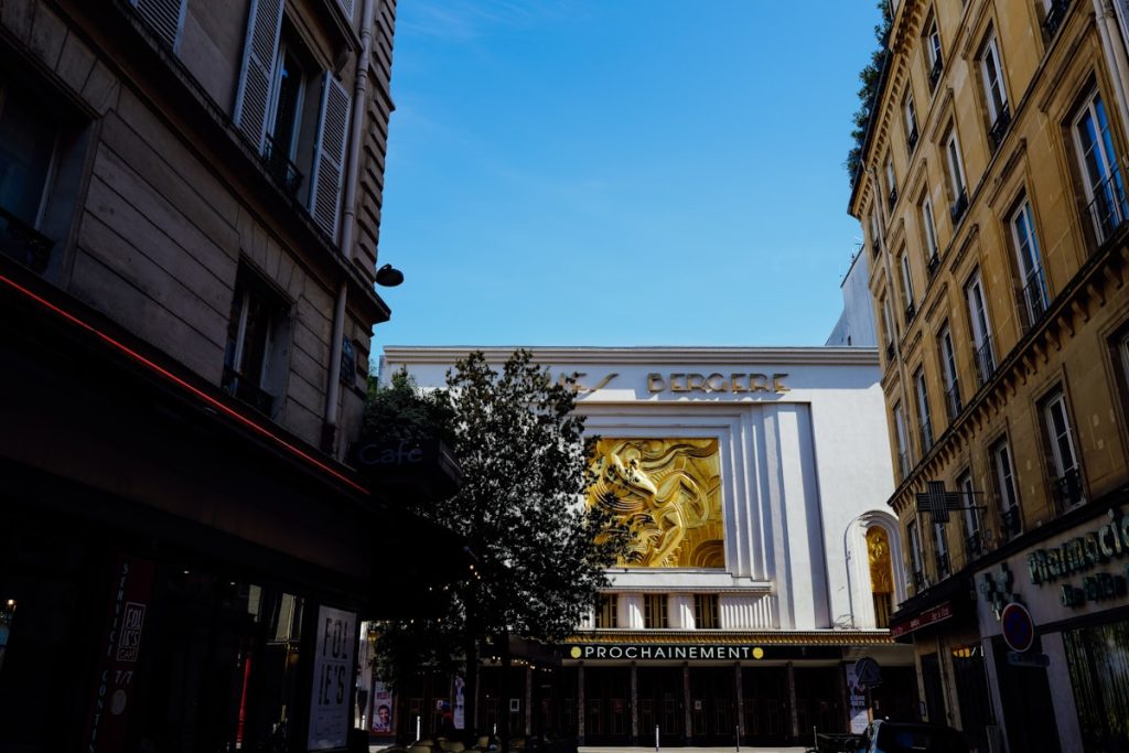 Ornate golden cinema facade framed by narrow Paris city streets, historic French theater