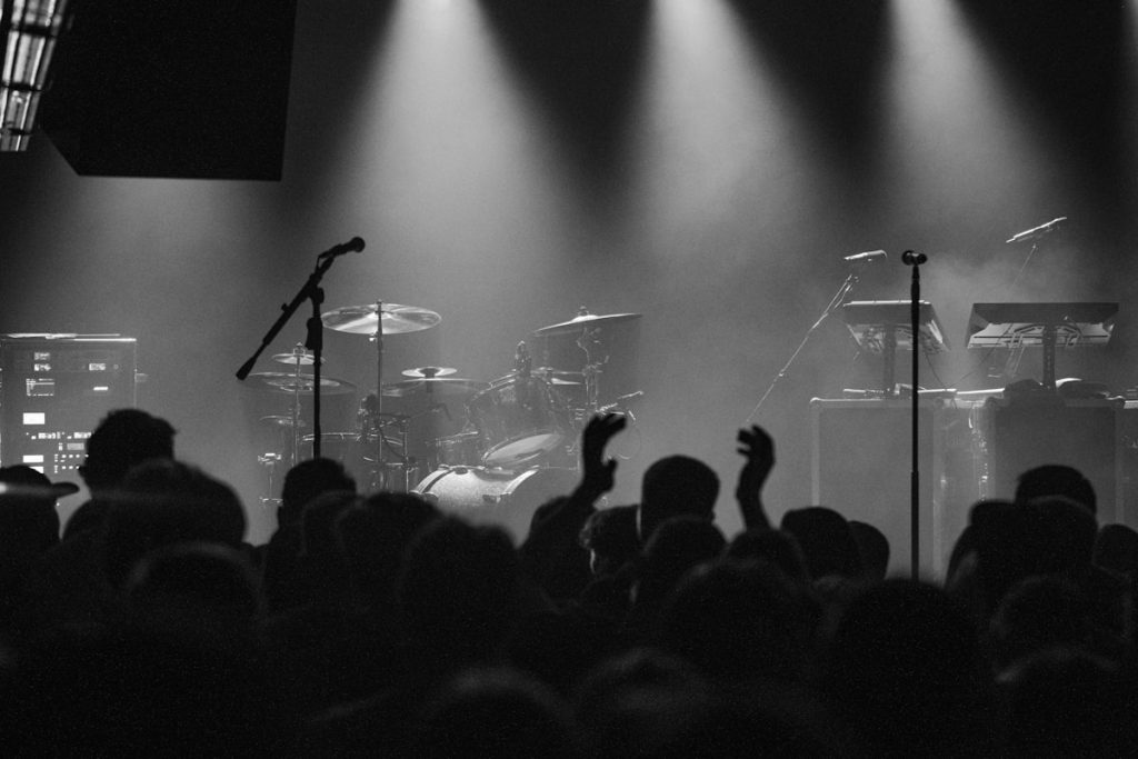 Concert crowd with stage lights, microphone, keyboard and instruments, live music festival atmosphere