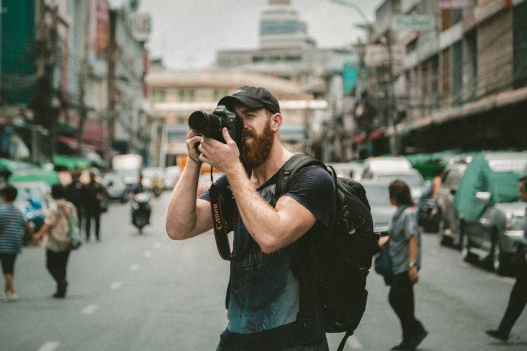 Shallow focus photography of a person using a DSLR camera in an urban setting in Bangkok