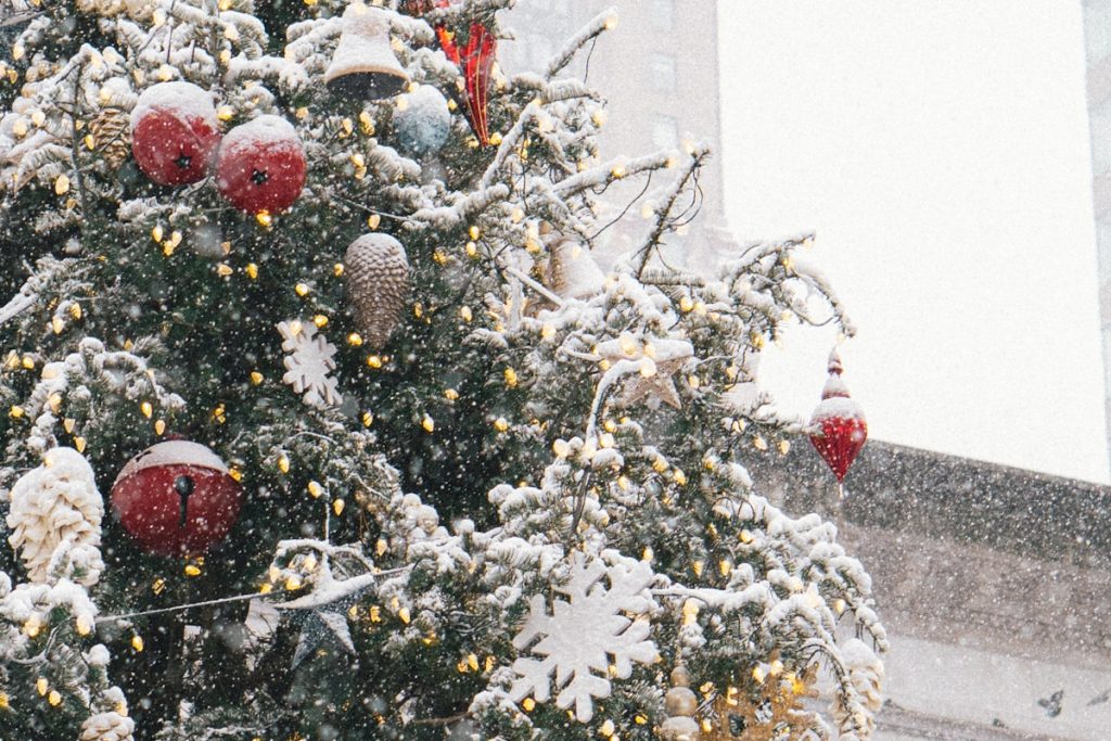 Decorated Christmas tree in falling snow in New York City, festive winter holiday scene
