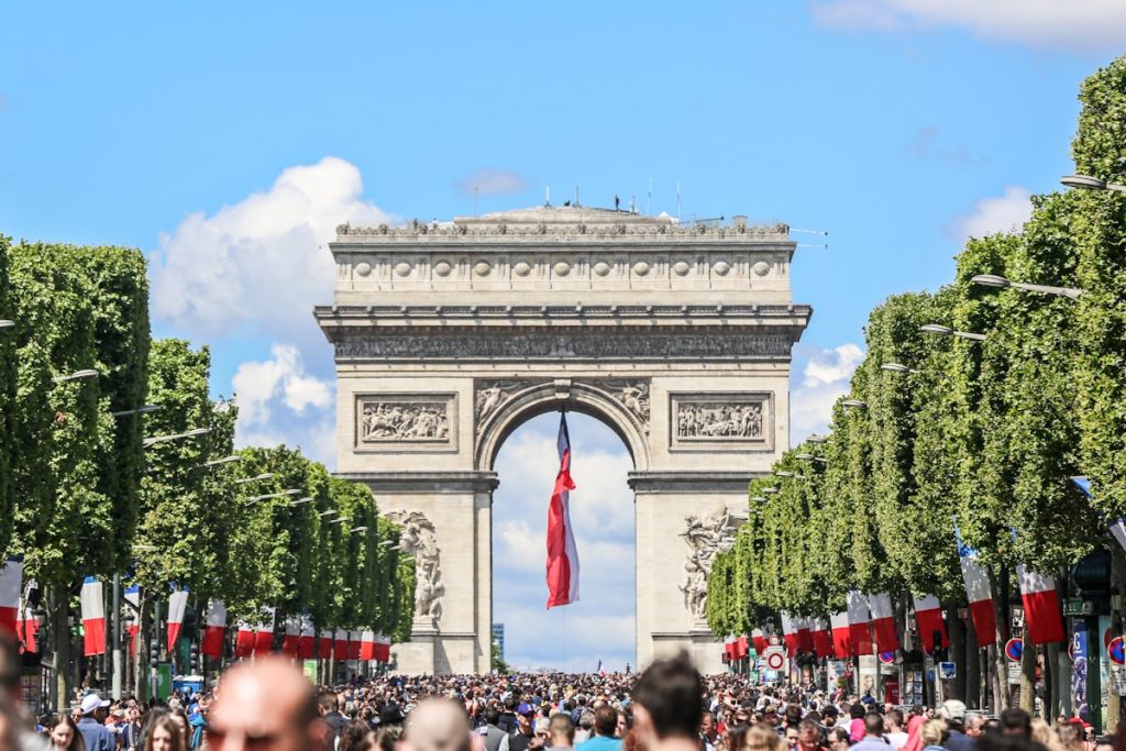 Arc de Triomphe with French national flag and crowd on Bastille Day celebration in Paris